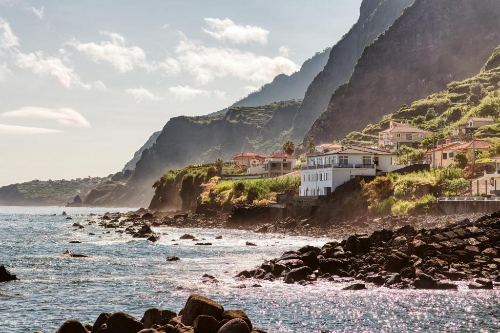 a view of the ocean with houses on a cliff at The Waves Hostel in São Vicente