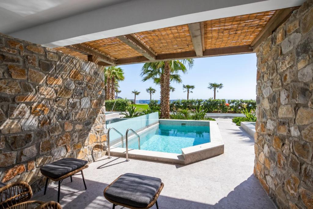 an outdoor patio with a swimming pool and a stone wall at Konstantinos Palace in Karpathos