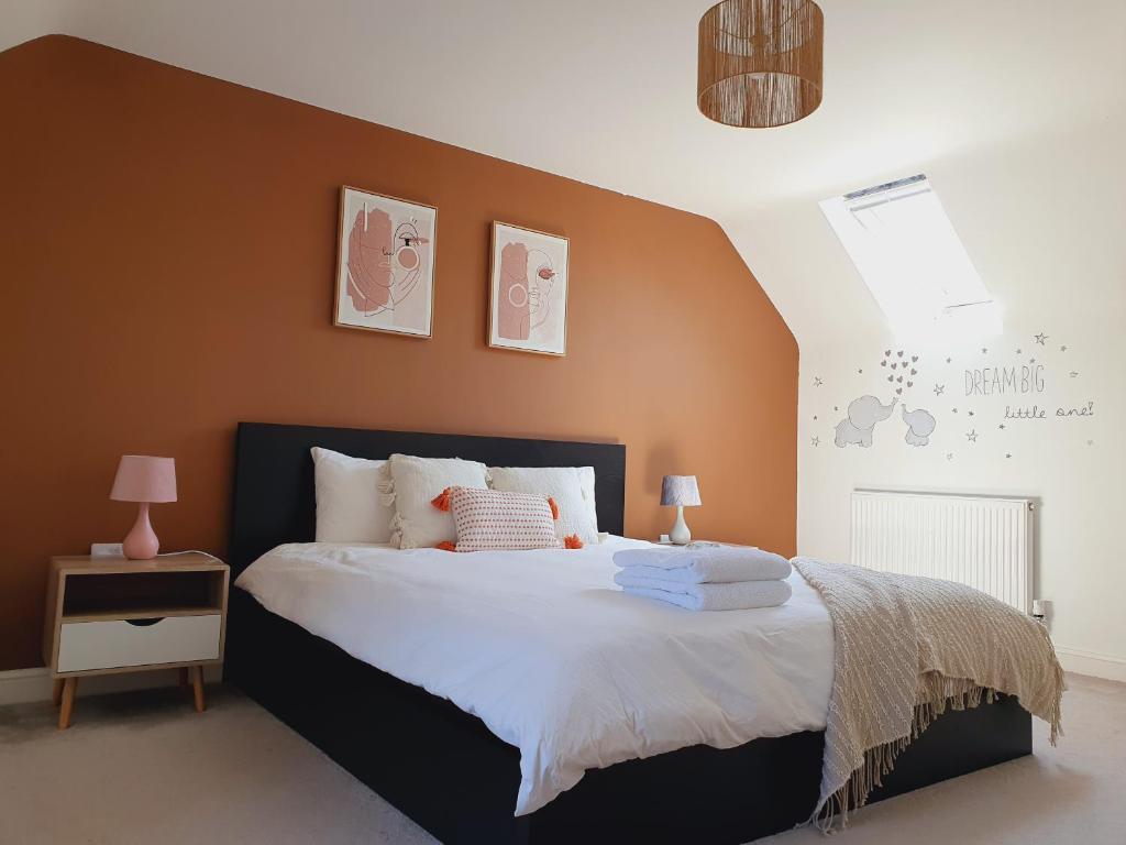 a bedroom with a large bed with orange walls at Queensize private room - en suite and free parking in Silverdale