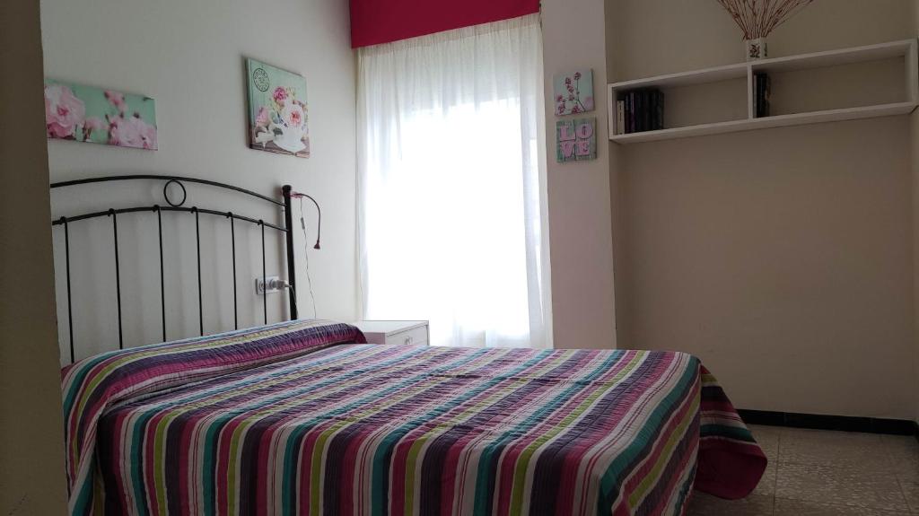 - une chambre avec un lit avec une couverture rayée et une fenêtre dans l'établissement Amplio piso en Pontedeume, à Pontedeume