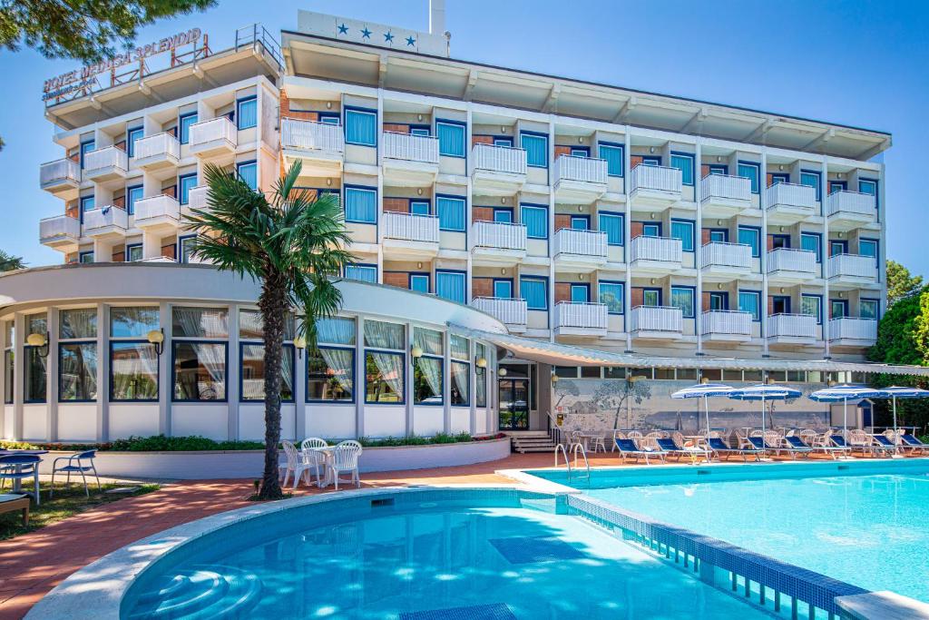 a hotel with a swimming pool in front of a building at Hotel Medusa Splendid in Lignano Sabbiadoro