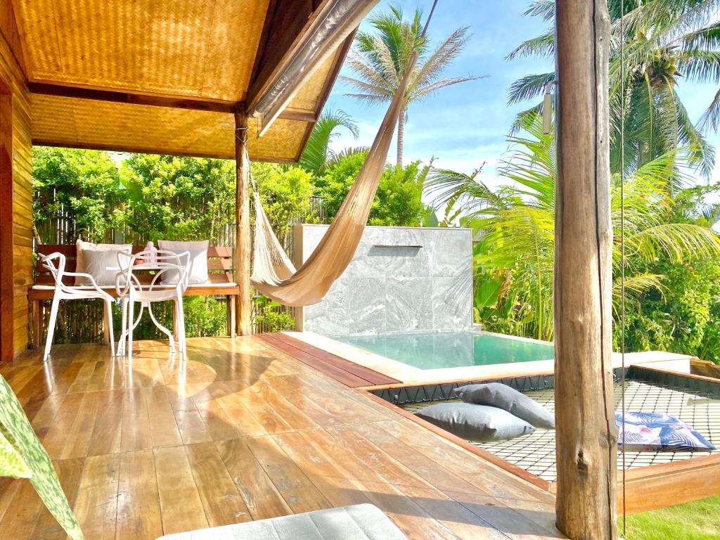 a patio with a hammock and a swimming pool at Nibbana Bungalows in Hinkong