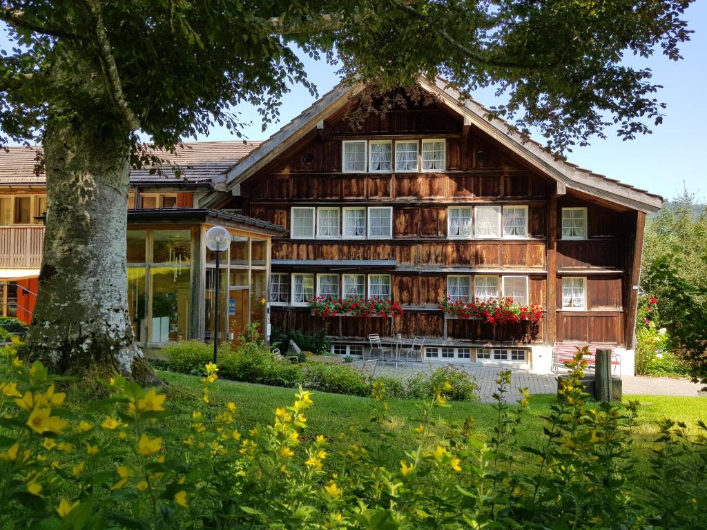 a wooden house with a tree in front of it at Ferienhotel Idyll Gais in Gais