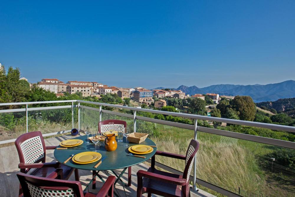 un tavolo e sedie su un balcone con vista di Gîte Du Pont - Piana a Piana