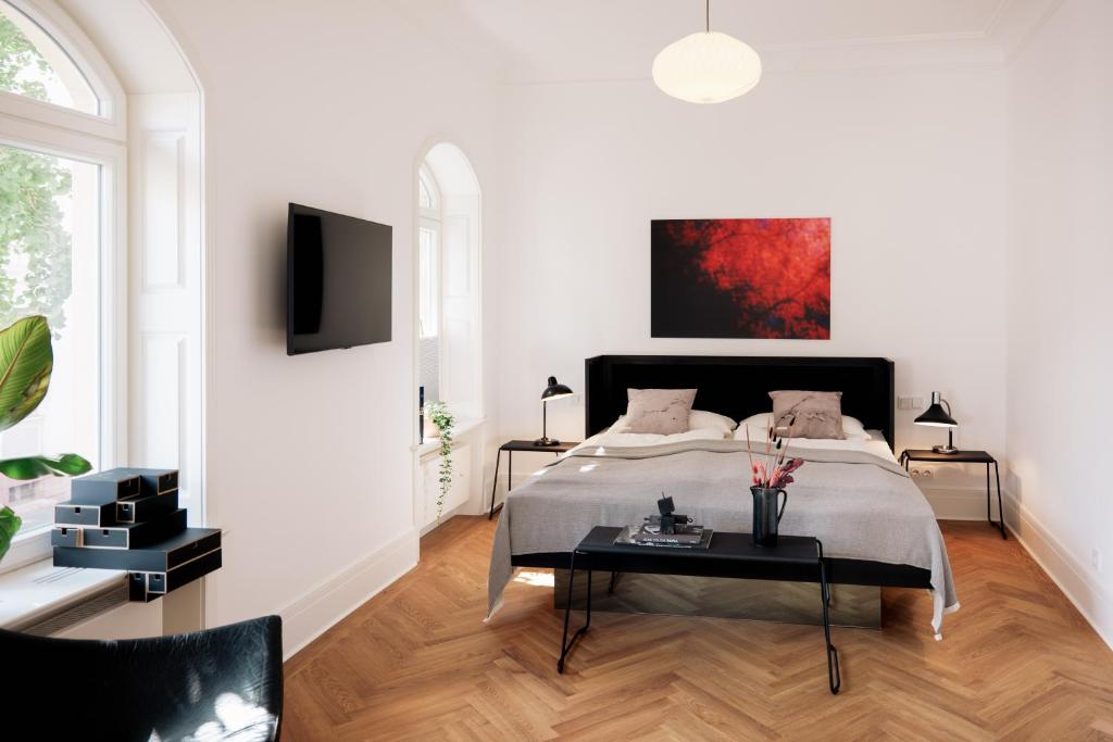 a white bedroom with a bed and a table at WELL Pretty Places - sustainable interior design in the Citycenter in Kassel