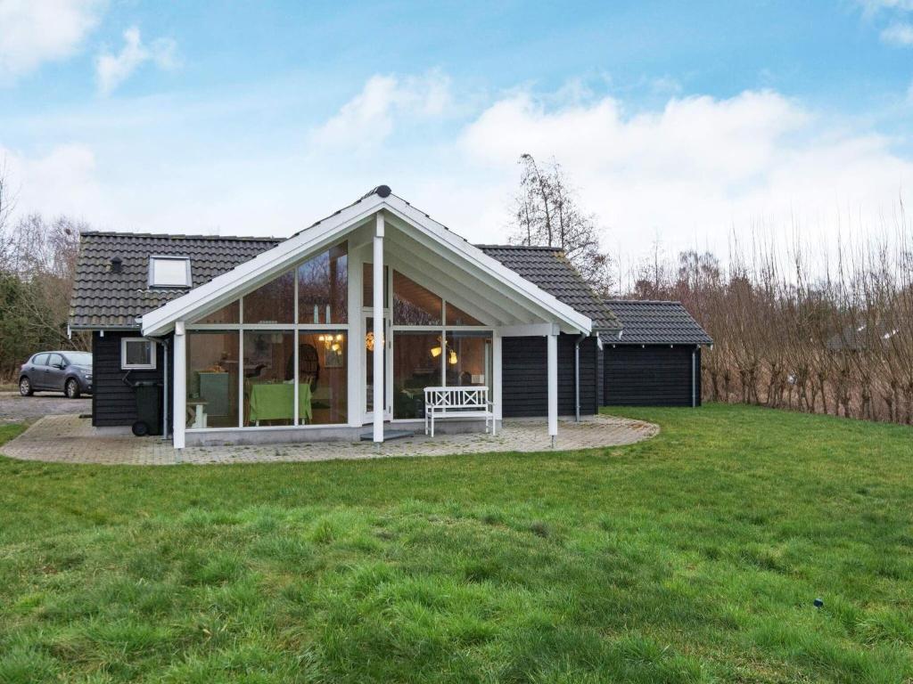 a house with a conservatory with a green lawn at 6 person holiday home in Ebeltoft in Ebeltoft