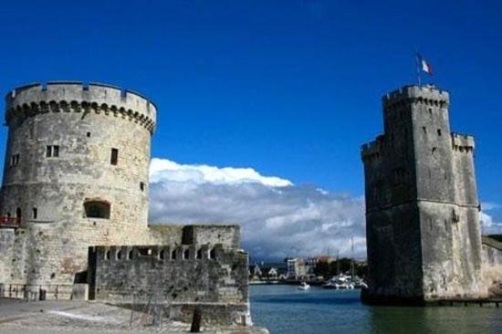 un château avec deux tours à côté d'une étendue d'eau dans l'établissement Le Cosy des Minimes, à La Rochelle