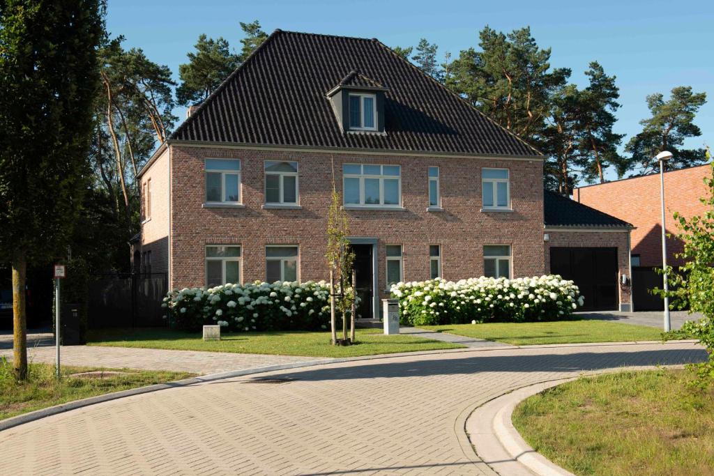 una casa de ladrillo con flores blancas delante de ella en StudioBeerse met Sauna Zwembad en Spa en Beerse