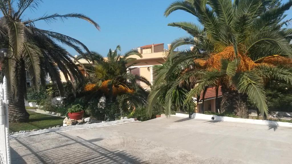 a villa with palm trees in front of a building at Natassa House 2 in Agios Georgios Pagon