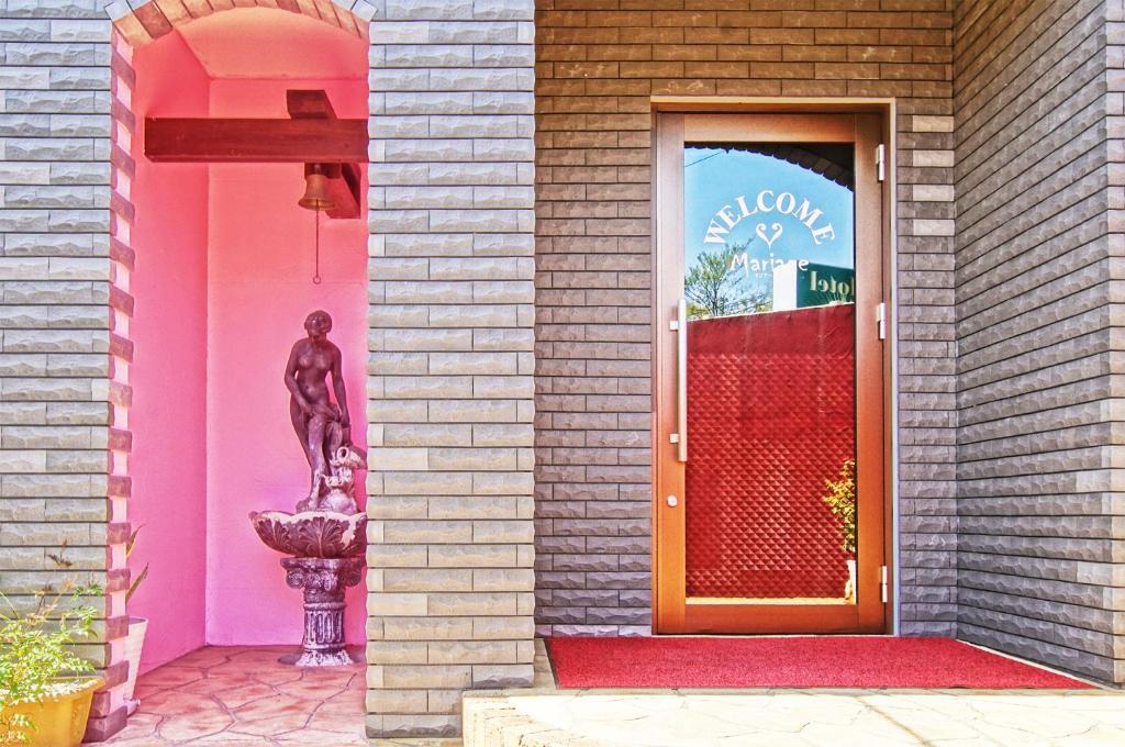 un bâtiment rose avec une statue devant une porte dans l'établissement Mariage Leisure Hotel, à Tsukuba