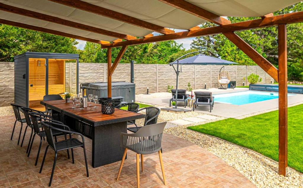 un patio con mesa y sillas junto a una piscina en Villa Uno Balaton en Balatonakarattya