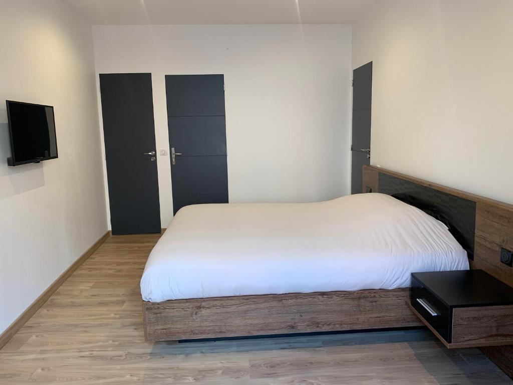 a bedroom with a white bed and a tv at Chambre avec entrée indépendante in Lamastre