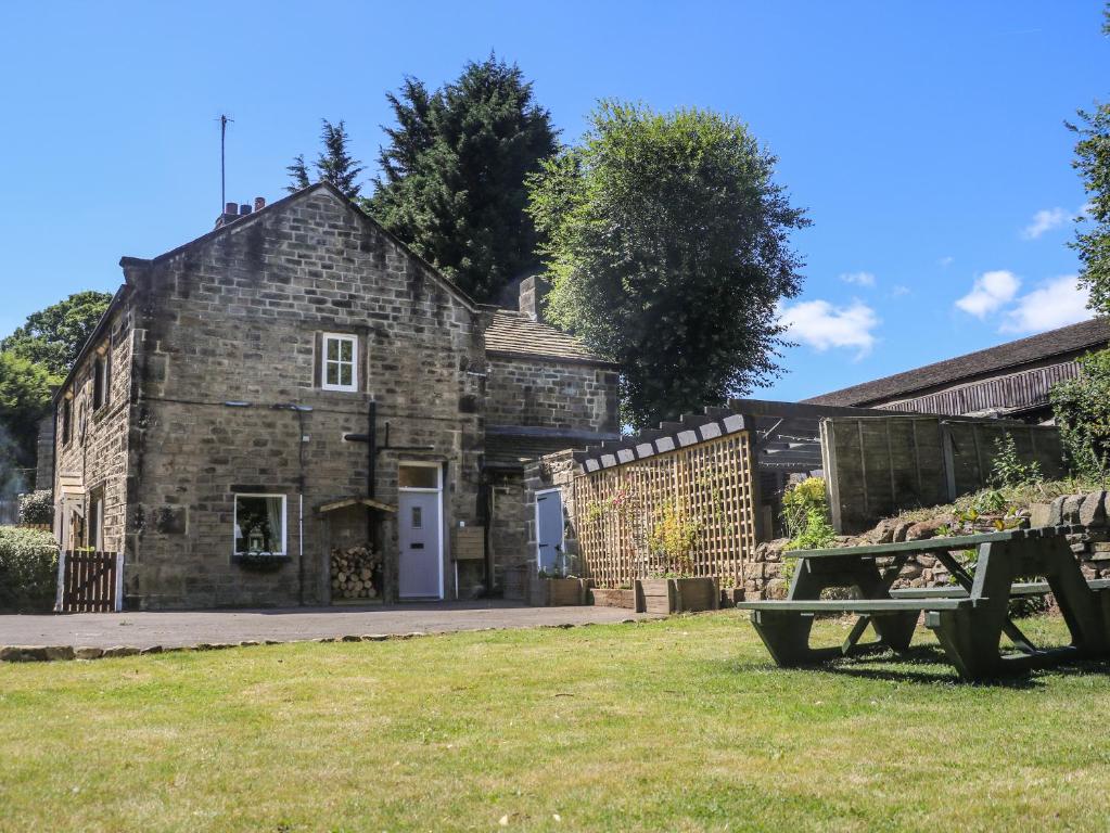 an old stone building with a picnic table in the grass at Tulip Cottage in Shipley