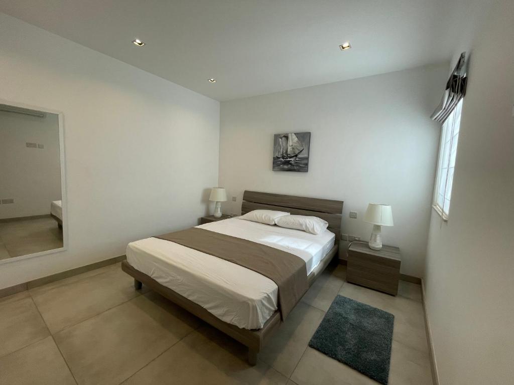 Balzan Luxury Living في Ħal Balzan: غرفة نوم بيضاء مع سرير ومرآة