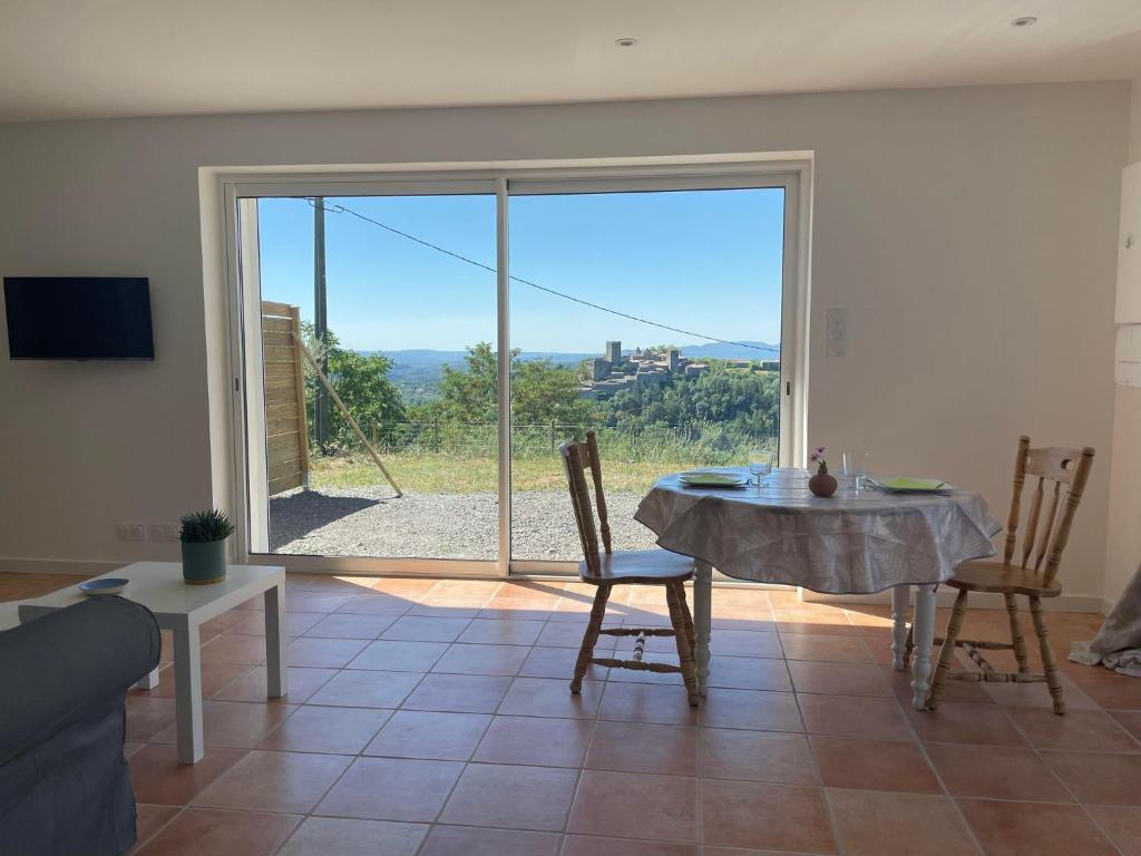 uma sala de estar com uma mesa e uma grande porta de vidro deslizante em Gîte Les Mimosas - 2 à 4 personnes - Vue imprenable em Largentière