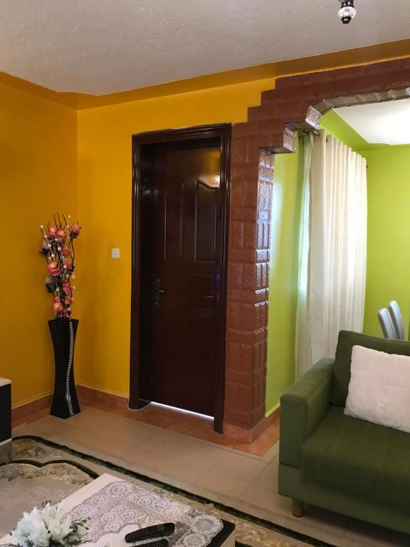 a living room with a green couch and yellow walls at Maliaways Comfy Airbnb-Jkia in Nairobi