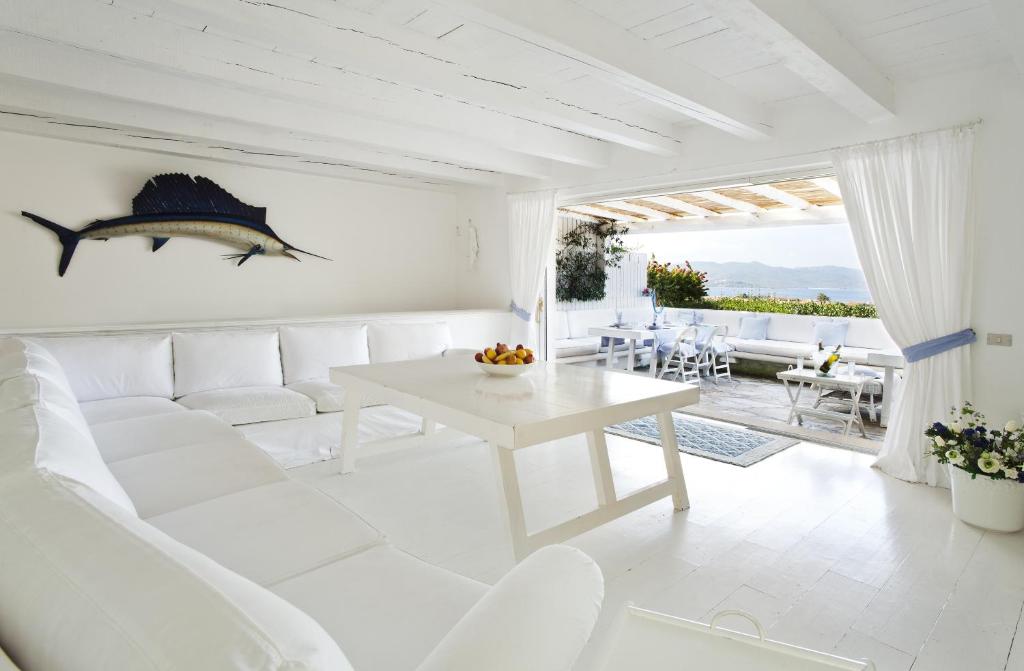 a white living room with a white couch and a table at Villa dei Tramonti in Porto Rotondo