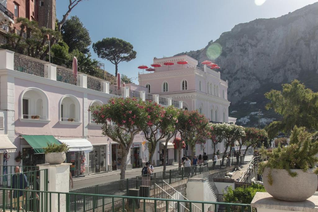 eine Straße mit Gebäuden, Bäumen und einem Berg in der Unterkunft Il Capri Hotel in Capri