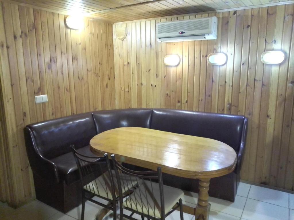 a table and a leather couch with a table and chairs at Rodina Hotel in Odesa