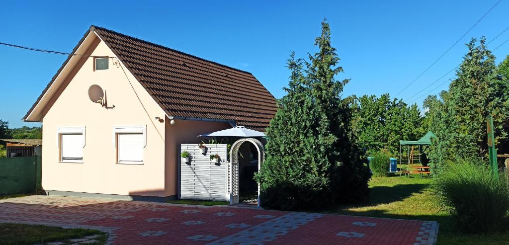 a small white building with a door in a yard at Önálló, klimatizált, medencés nyaraló a Balatonnál! in Kőröshegy