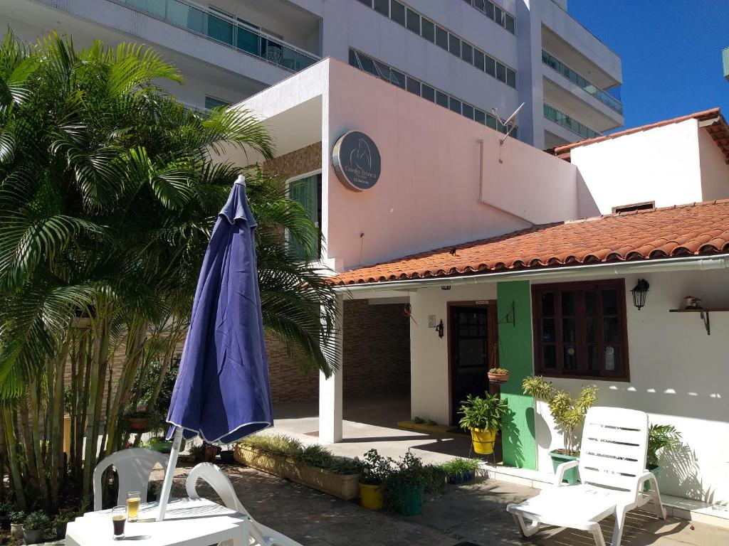 a blue umbrella and two chairs and a building at Pousada Cavalo Branco in Cabo Frio