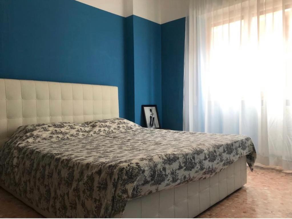 a bedroom with a bed with blue walls and a window at Trastevere room in Rome