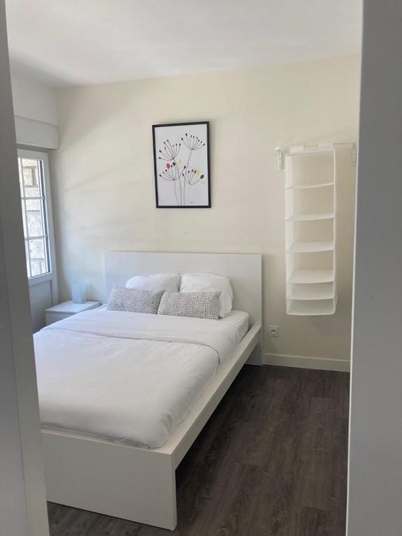 ein weißes Schlafzimmer mit einem Bett mit weißer Bettwäsche und Kissen in der Unterkunft Appart proche gare salle de sport vidéoprojection in Agen