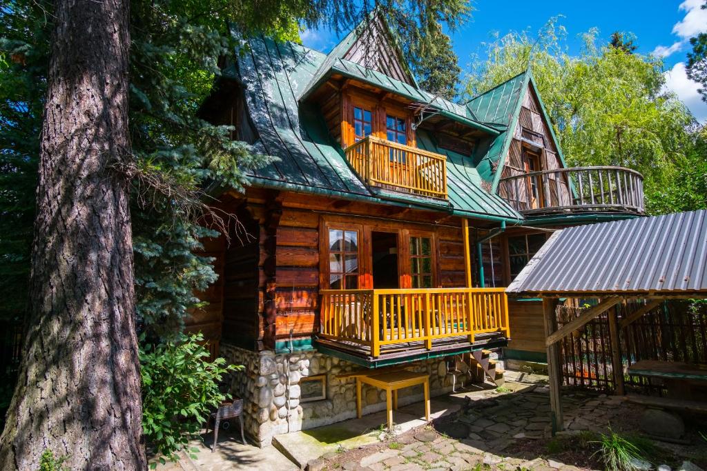 a log cabin with a balcony and a tree at Gorski dom Gubalowka in Zakopane