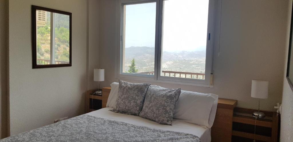 a bedroom with a bed with two pillows and two windows at Mirador Castillo La Iruela in Cazorla