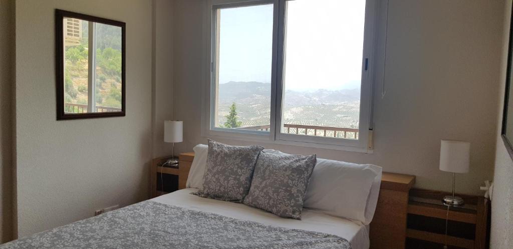 1 dormitorio con 1 cama con 2 almohadas y 2 ventanas en Mirador Castillo La Iruela, en Cazorla