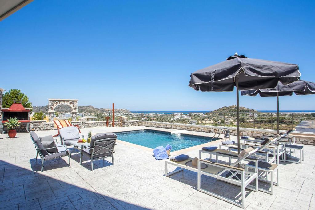 a patio with chairs and an umbrella and a pool at Des & Coo Luxury Villa with Private Pool in Faliraki
