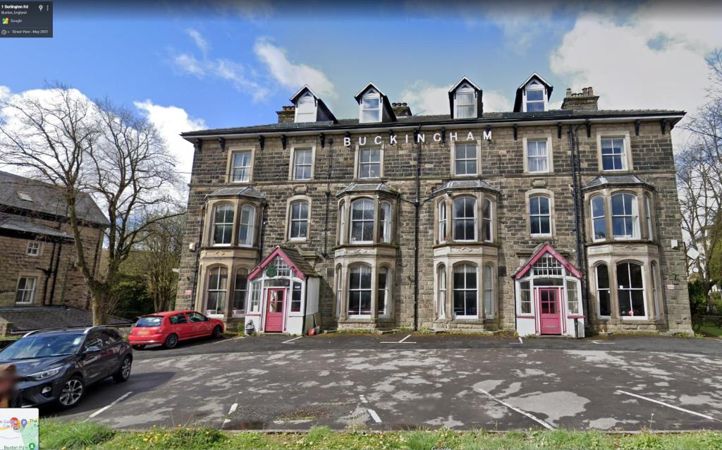 a large brick building with cars parked in a parking lot at Buckingham Hotel in Buxton