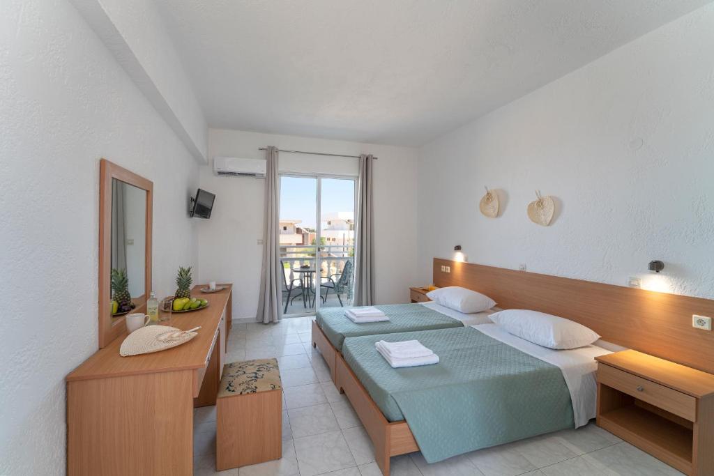 a bedroom with a bed and a desk and a balcony at Yiasemi Apartments in Faliraki