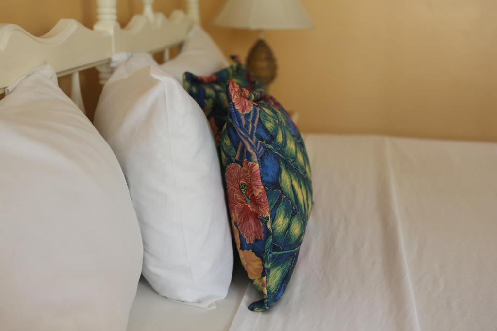 a bed with two pillows and a floral umbrella on it at Moonrisevillas in Negril
