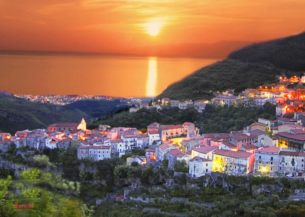 une ville sur une colline avec le coucher du soleil en arrière-plan dans l'établissement Petracuzza casa vacanze, à Tortora