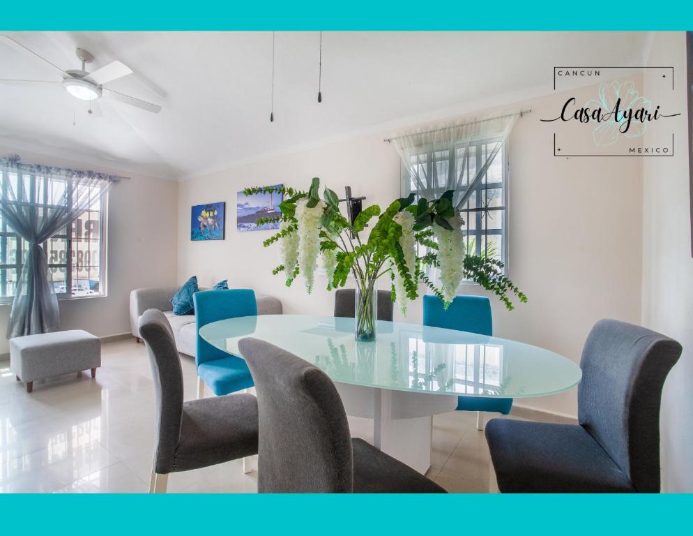 Casa Ayari - 3 Habitaciones - 2 a 6 personas - WIFI- AC في كانكون: غرفة طعام مع طاولة زجاجية وكراسي زرقاء