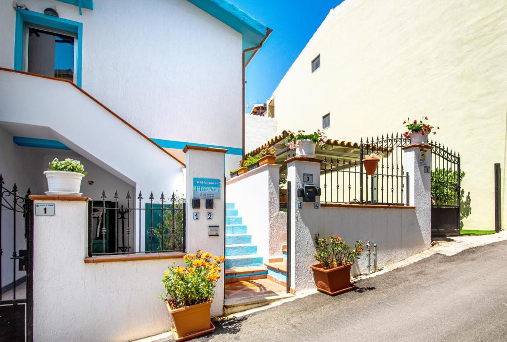 Deux maisons blanches avec des plantes en pot sur le côté d'une rue dans l'établissement Blue Sea, à Posada