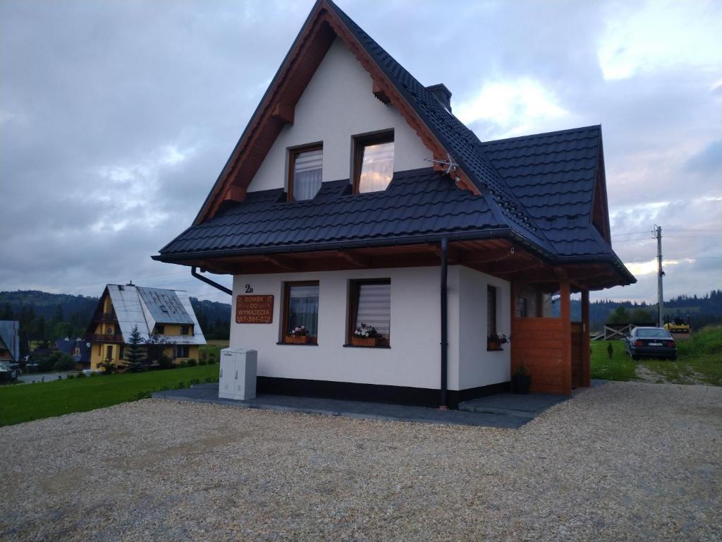 a small white house with a black roof at Domek u Mrugały in Poronin