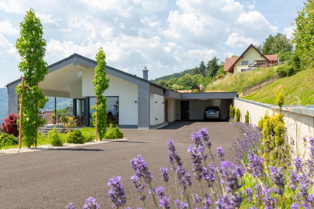ein Haus auf einem Hügel mit lila Blumen in der Unterkunft Greim15 --- ganzes Ferienhaus mit Fernsicht, Pool, Wellness in Deutschlandsberg