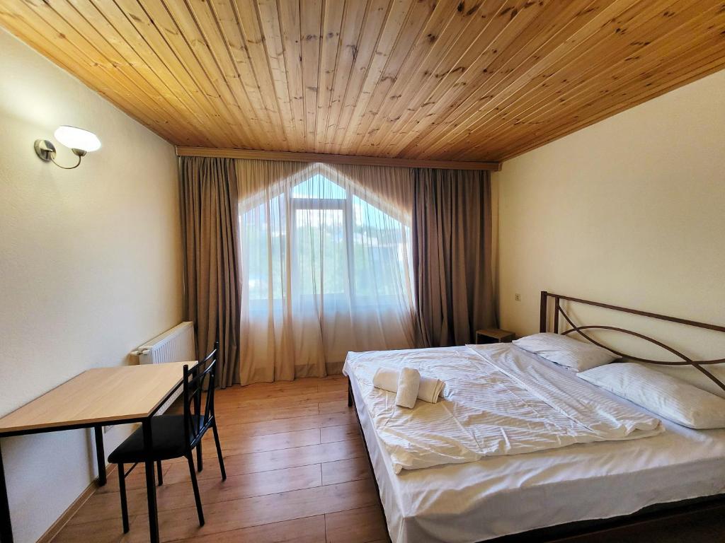 a bedroom with a bed and a table and a window at Homelike B&B in Tbilisi City
