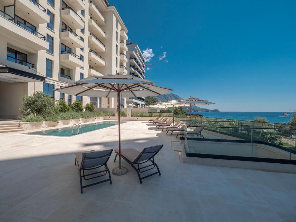 a patio with chairs and a table with an umbrella at CASA AL MARE RESIDENCE in Bečići