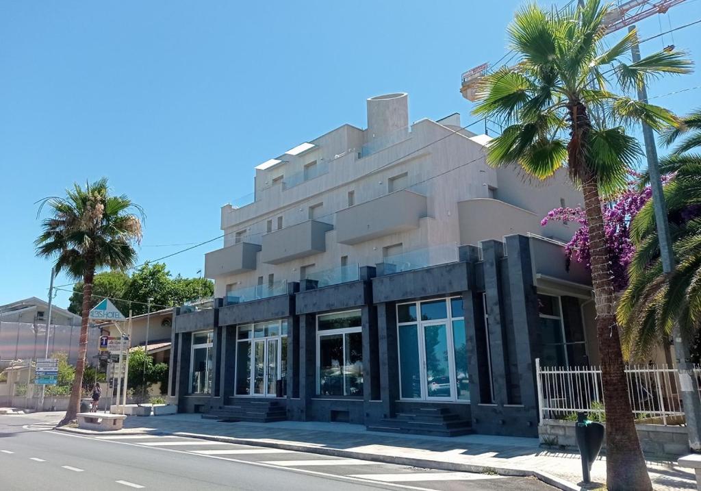 un bâtiment sur le côté d'une rue bordée de palmiers dans l'établissement Hotel Alb's, à Alba Adriatica