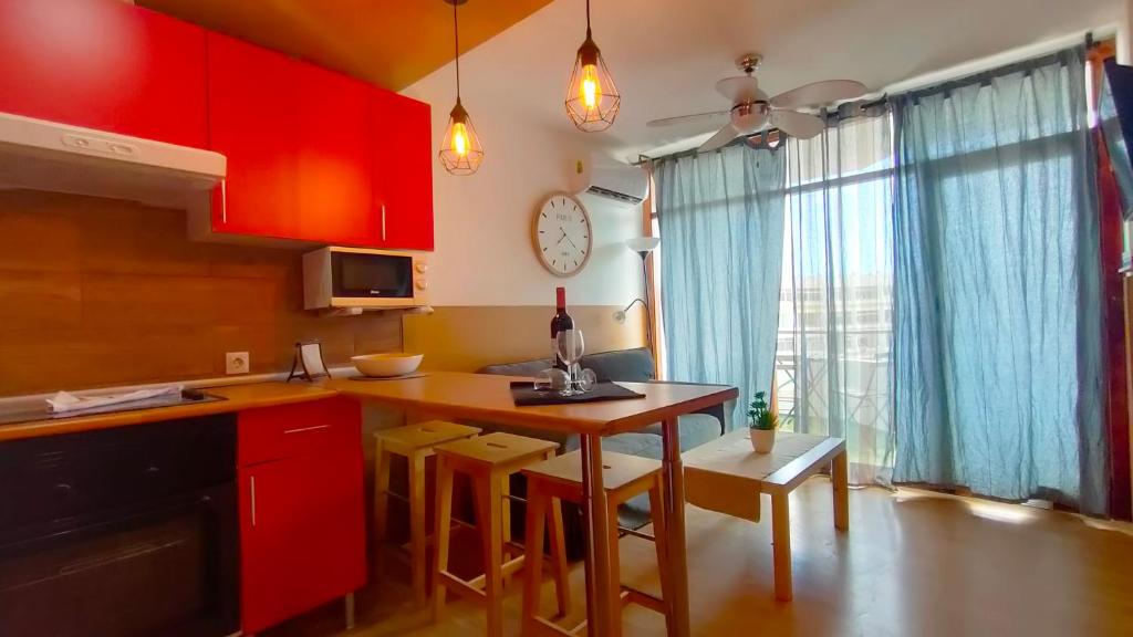 プラヤ・デル・イングレスにあるSea Friendly Holiday Homeのキッチン(赤いキャビネット、テーブル、スツール付)