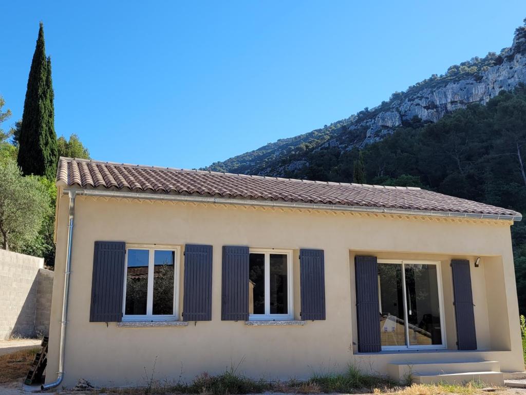 a small white house with a mountain in the background at L'Oustau de Laëtitia Animaux bienvenus in Fontaine-de-Vaucluse