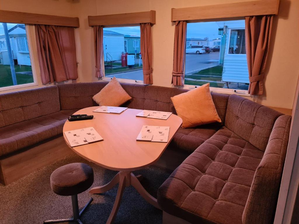 sala de estar con sofá y mesa en Cosy, family caravan near the beach en Clacton-on-Sea