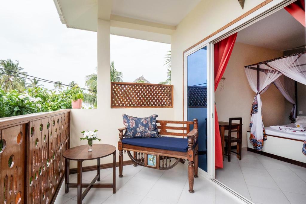a balcony with a chair and a table at Villa RaCoCo in Jambiani