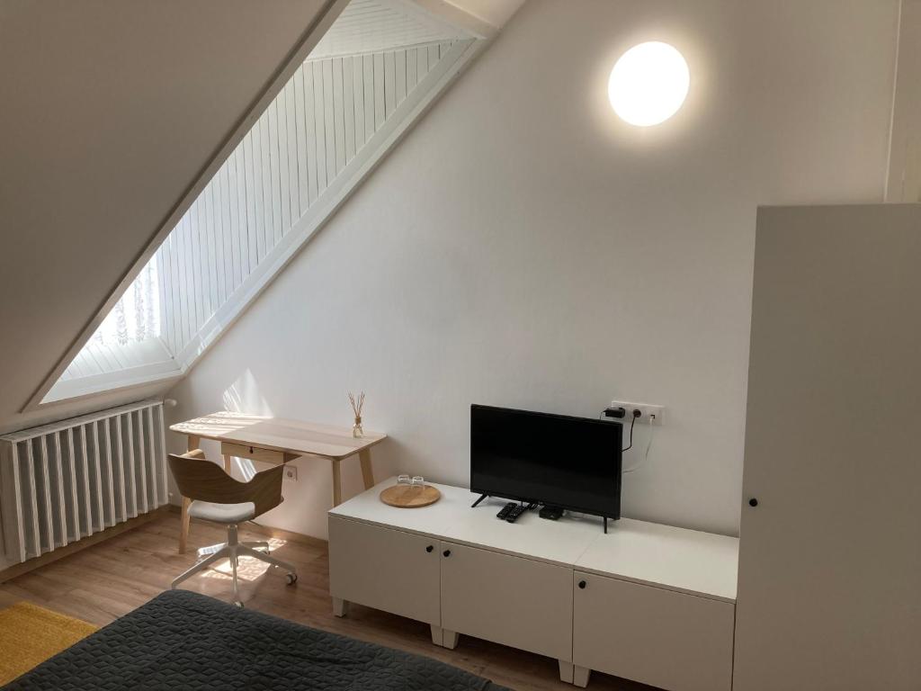 Habitación blanca con escritorio y TV. en Bólyi Panzió, en Bóly