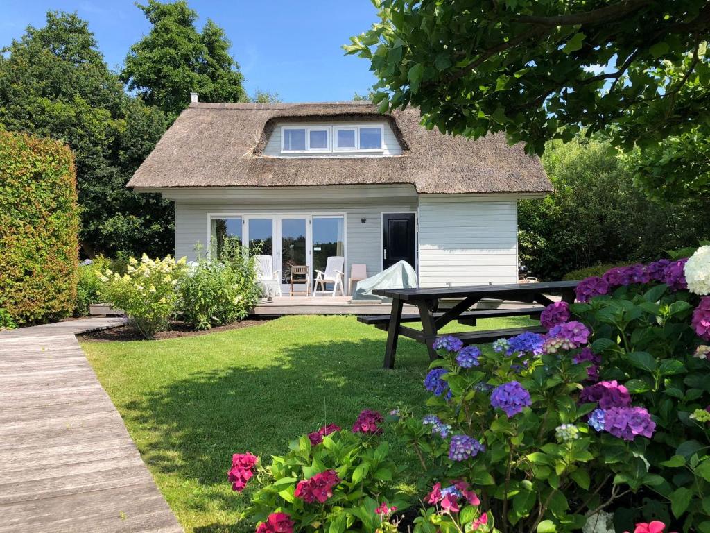 a small cottage with a picnic table and flowers at Idyllic Lakehouse - dog is welcome fenced garden in Haren