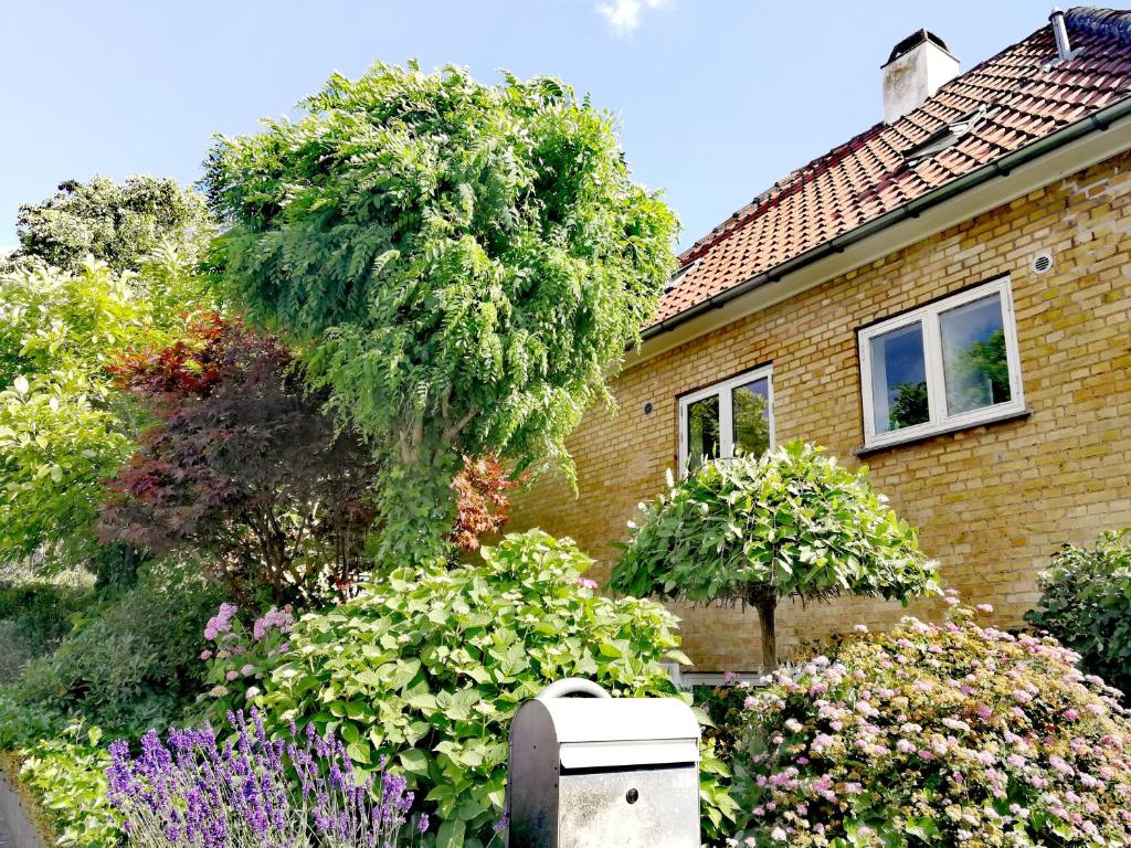 a house with a garden of flowers in front of it at Room in a Danish cottage with garden view, 10 min to CPH in Gentofte