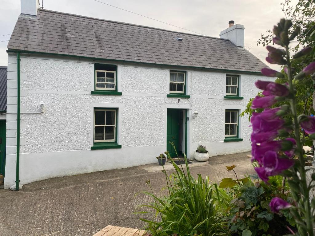 a white cottage with green windows and a driveway at Glenaan Cottage in Cushendall